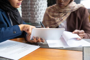 Dua orang sedang berdiskusi tentang dokumen di meja, mencerminkan pembahasan Hukum Deposito Syariah dalam transaksi keuangan.