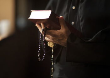 Seseorang memegang Al-Qur'an dengan tasbih, simbol ketenangan dan ibadah dalam kehidupan spiritual. Terkait dengan prinsip-prinsip Deposito Syariah yang mengutamakan kesucian dan kehalalan dalam transaksi keuangan.