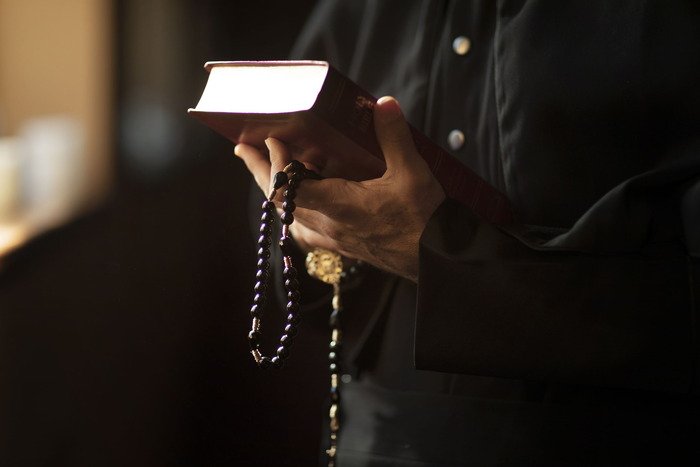 Seseorang memegang Al-Qur'an dengan tasbih, simbol ketenangan dan ibadah dalam kehidupan spiritual. Terkait dengan prinsip-prinsip Deposito Syariah yang mengutamakan kesucian dan kehalalan dalam transaksi keuangan.
