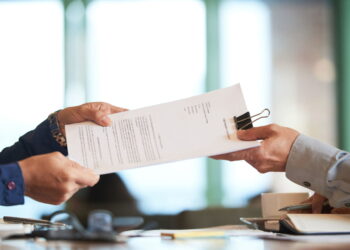 Dua orang sedang memberikan Sertifikat Deposito