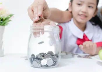 Seorang anak sedang di ajarkan menabung oleh orang tuanya