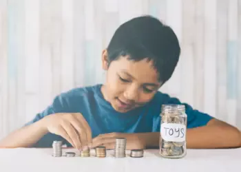 Seorang anak kecil sedang menyisihkan uangnya untuk di tabung