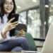 gambar seorang wanita melihat ke arah smartphone nya dan sedang memegang kartu atm