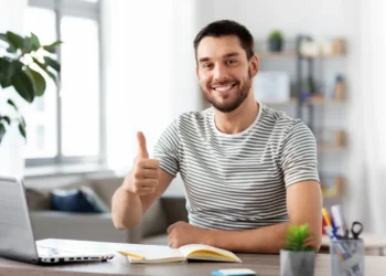 Laki-laki baju bergaris hijau gelap tersenyum