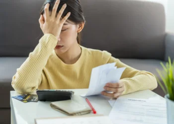 Seorang wanita baju kuning sedang khawatir terkait utangnya