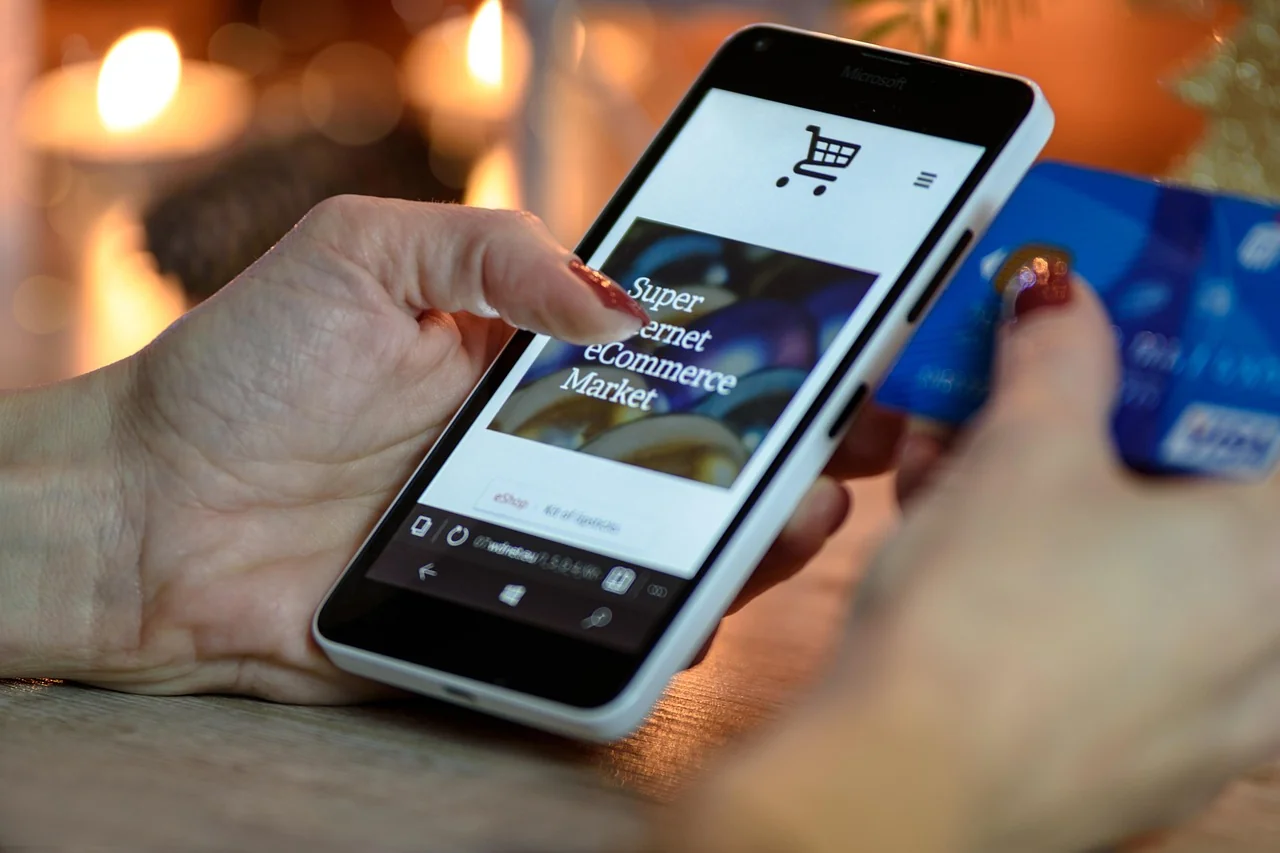 Belanja online lewat smartphone sambil memegang kartu