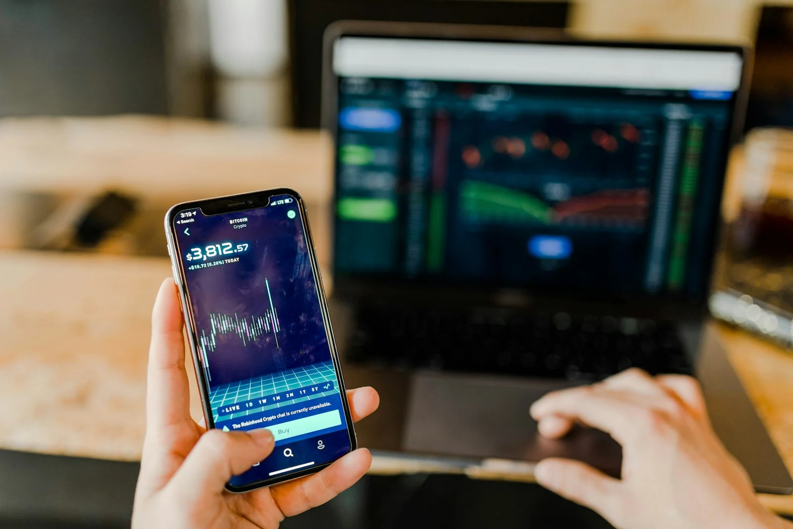 Investor mengecek aplikasi saham di ponsel dan laptop