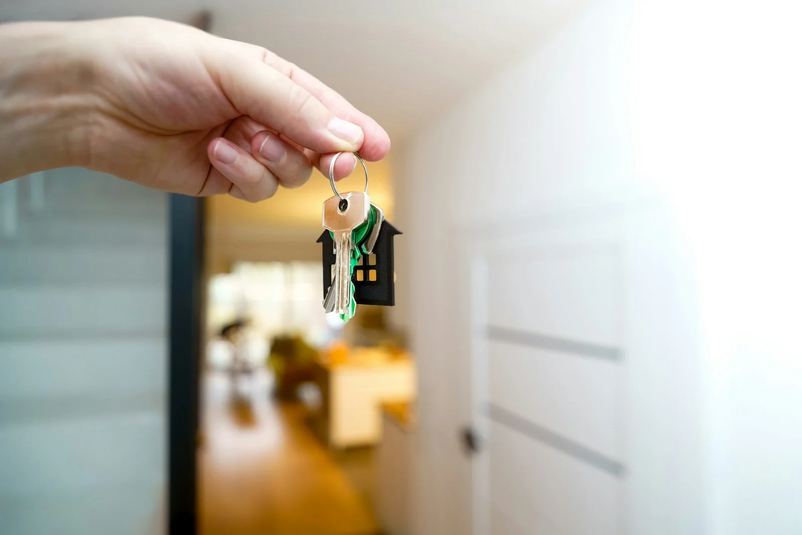 Tangan memegang kunci rumah di depan pintu masuk