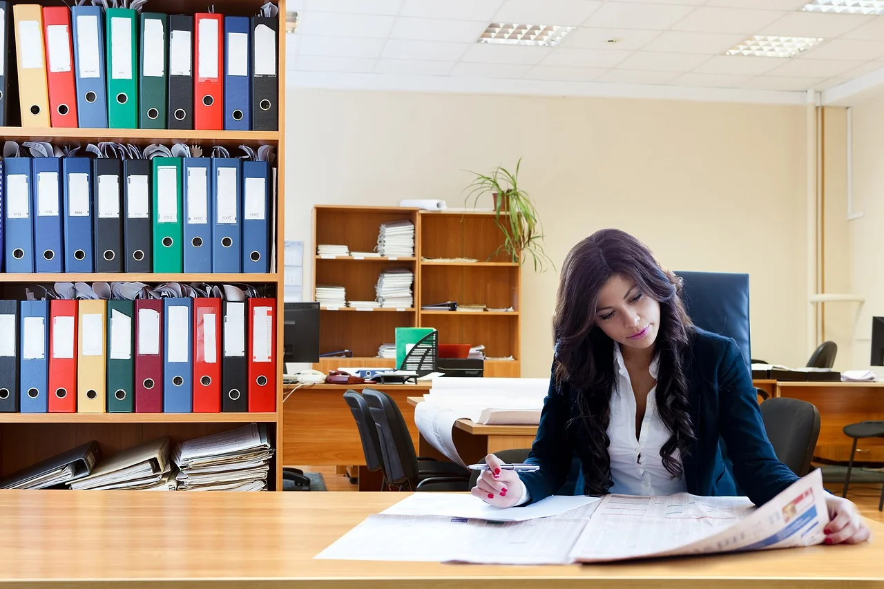 Perempuan memeriksa lembaran dokumen keuangan di meja kantor