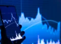 Ponsel dengan aplikasi saham di depan layar grafik