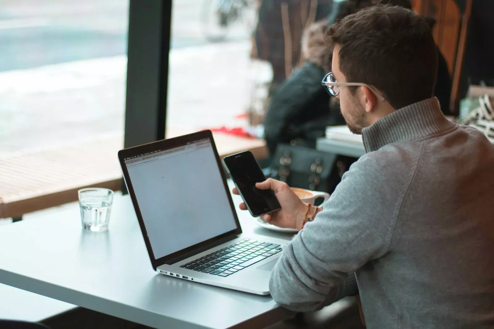 Pemilik usaha memeriksa saldo rekening lewat ponsel dan laptop