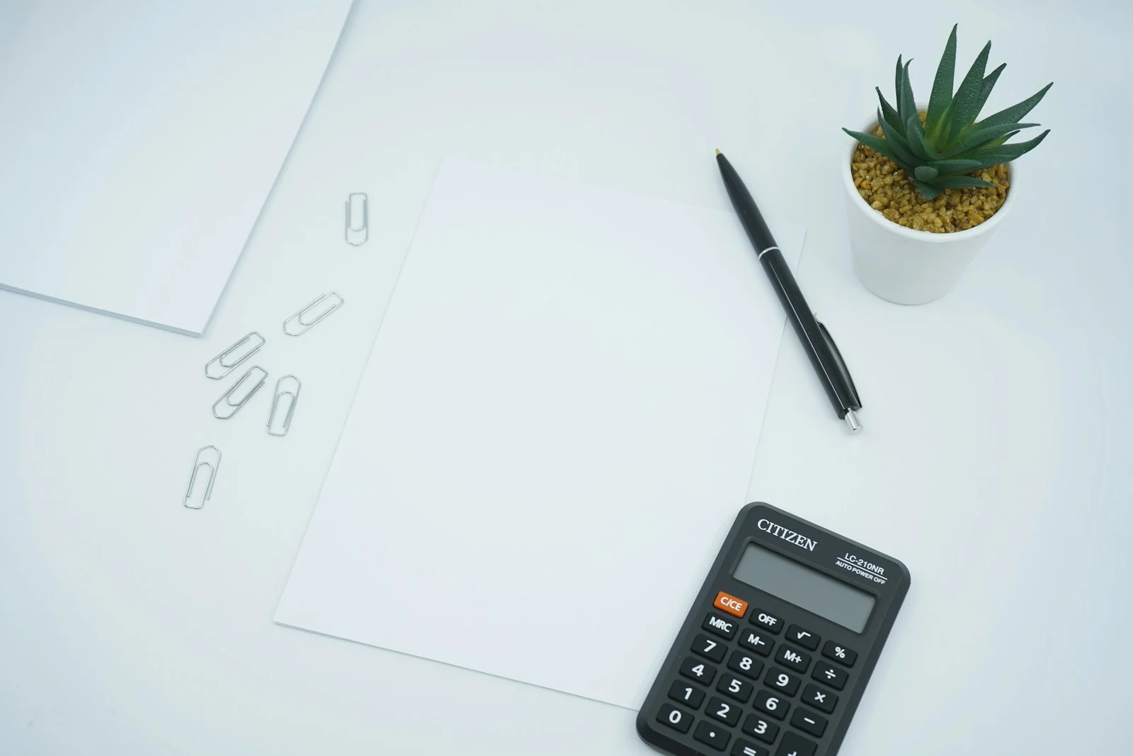 Kertas kosong, pulpen, dan kalkulator di meja untuk mencocokkan rekap pajak bagi hasil