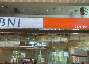 Papan nama BNI berwarna putih dan oranye bertuliskan Central Park di atas pintu kaca kantor cabang BNI