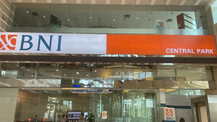 Papan nama BNI berwarna putih dan oranye bertuliskan Central Park di atas pintu kaca kantor cabang BNI