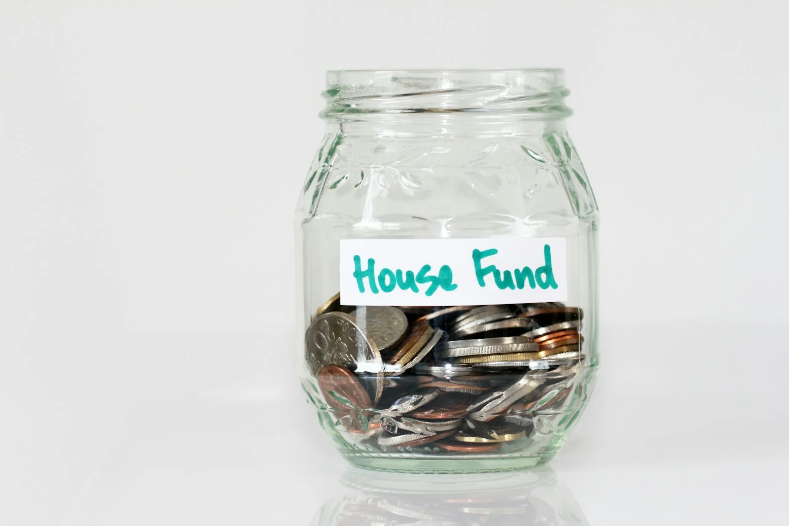 Stoples kaca berisi koin dengan label House Fund untuk tabungan rumah