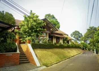 Rumah beratap genteng dengan tangga bata di lingkungan perumahan