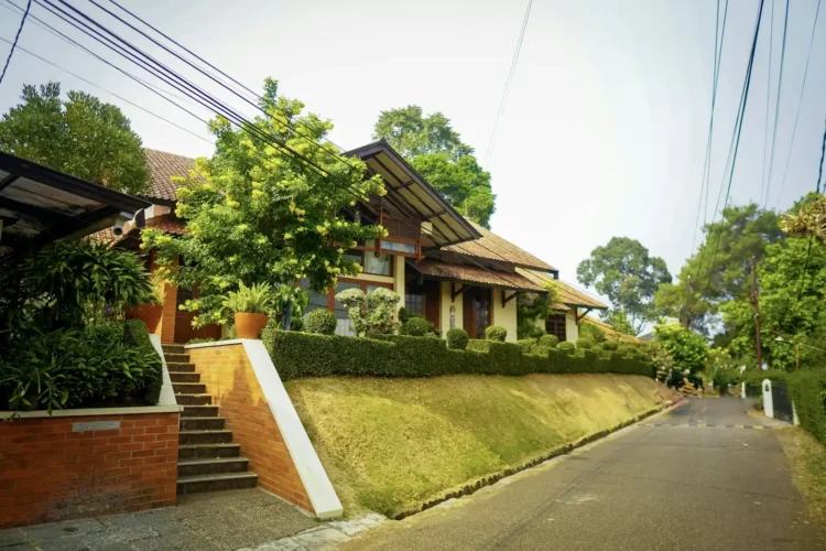 Rumah beratap genteng dengan tangga bata di lingkungan perumahan