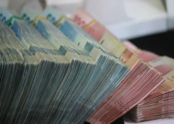 Tumpukan uang kertas rupiah pecahan 50.000 dan 100.000 yang diikat per bundel