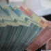 Tumpukan uang kertas rupiah pecahan 50.000 dan 100.000 yang diikat per bundel