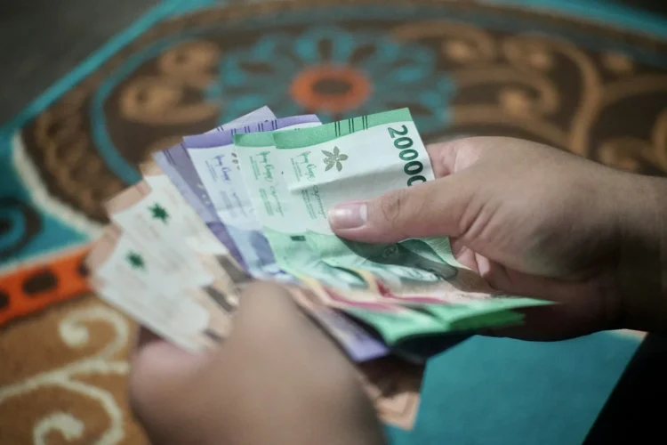 Tangan menghitung lembaran uang kertas rupiah emisi 2022