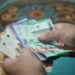 Tangan menghitung lembaran uang kertas rupiah emisi 2022
