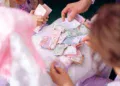 Tangan orang dewasa dan anak memilah uang kertas di atas meja