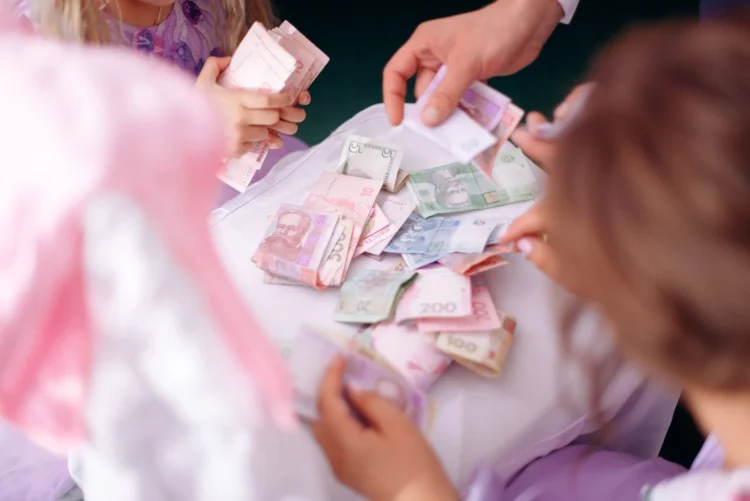 Tangan orang dewasa dan anak memilah uang kertas di atas meja