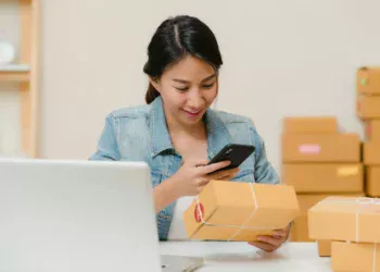 Pelaku usaha online memeriksa pesanan dan aplikasi bank di ponsel