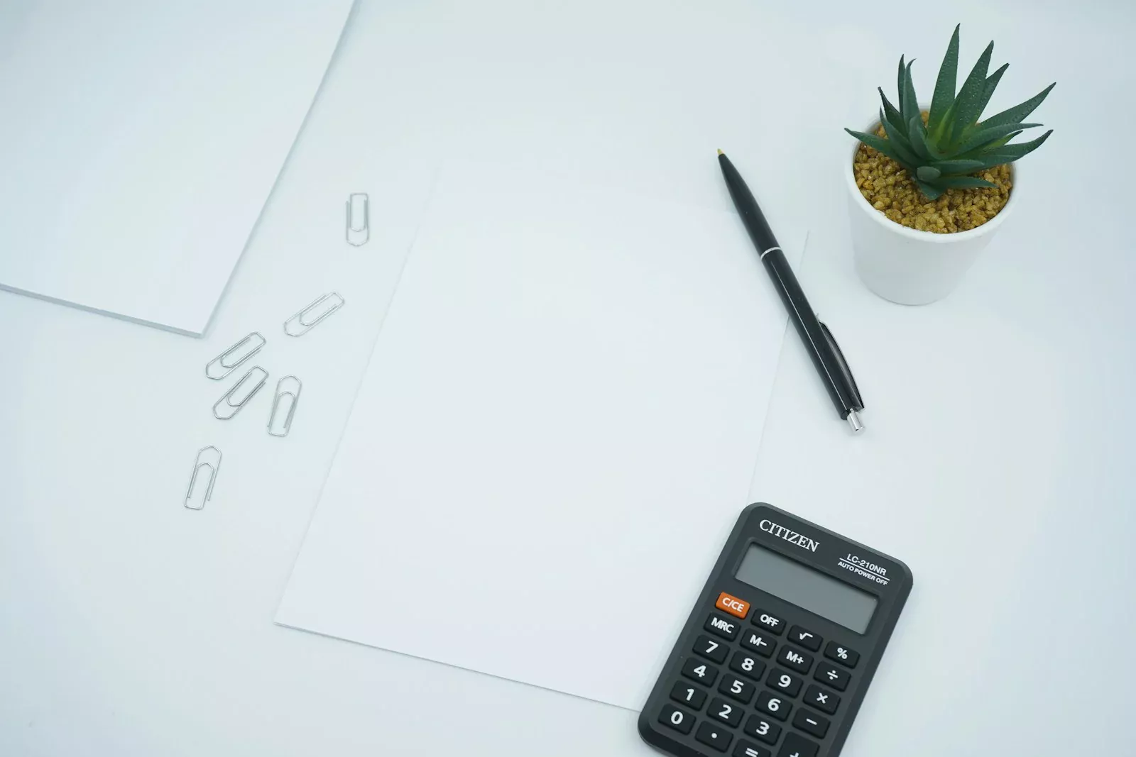 Kertas kosong, pulpen, dan kalkulator di meja untuk mencocokkan rekap pajak bagi hasil