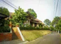 Rumah beratap genteng dengan tangga bata di lingkungan perumahan