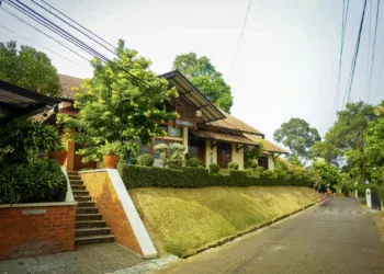 Rumah beratap genteng dengan tangga bata di lingkungan perumahan