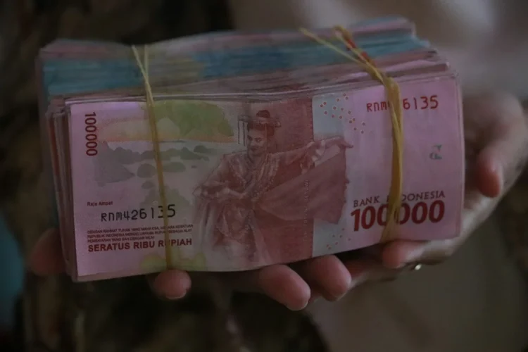 Tangan memegang uang rupiah pecahan Rp100.000