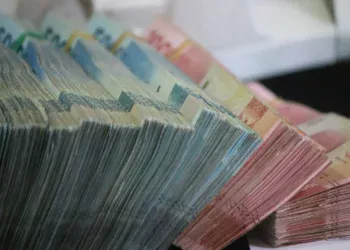 Tumpukan uang kertas rupiah pecahan 50.000 dan 100.000 yang diikat per bundel