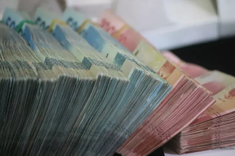 Tumpukan uang kertas rupiah pecahan 50.000 dan 100.000 yang diikat per bundel