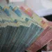 Tumpukan uang kertas rupiah pecahan 50.000 dan 100.000 yang diikat per bundel